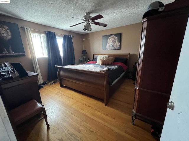 bedroom with ceiling fan, a textured ceiling, and light hardwood / wood-style flooring