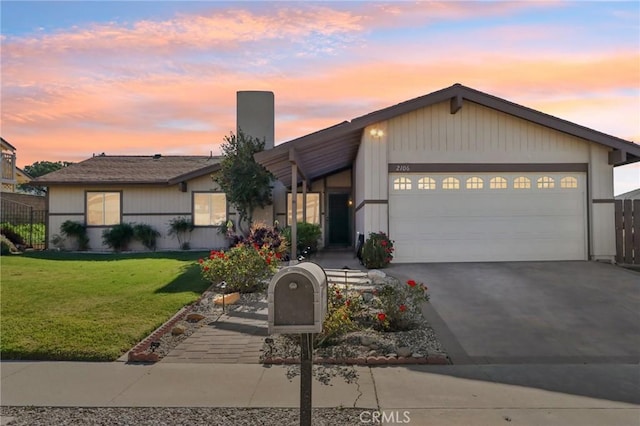 ranch-style home featuring a garage and a lawn