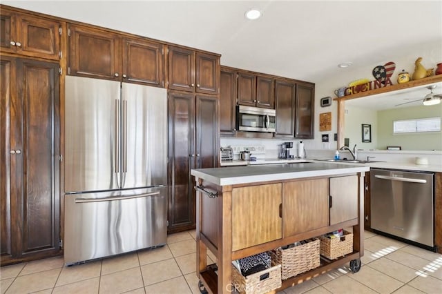 kitchen featuring sink, a center island, light tile patterned floors, ceiling fan, and stainless steel appliances