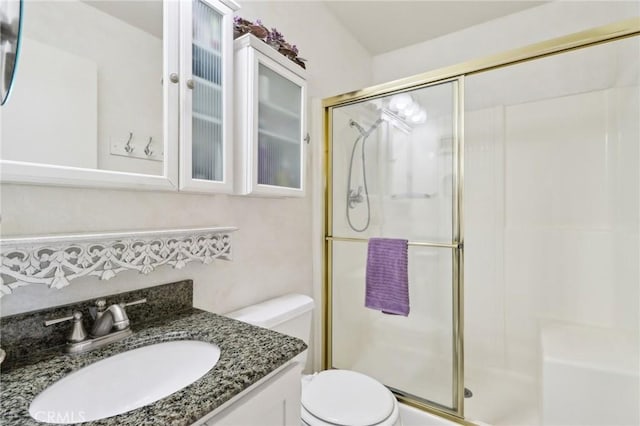 bathroom with an enclosed shower, vanity, and toilet