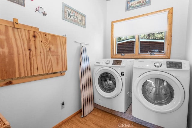 washroom with light wood-type flooring, laundry area, baseboards, and independent washer and dryer