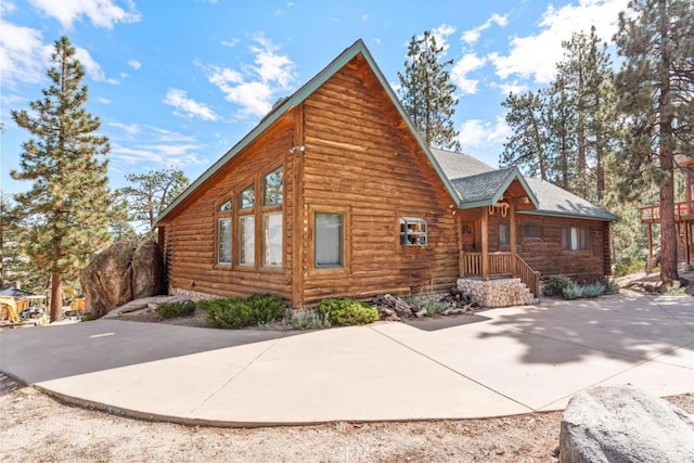 exterior space featuring a shingled roof and log siding