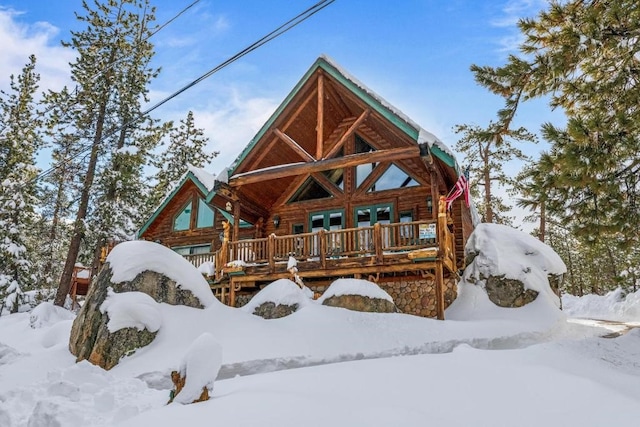 snow covered back of property featuring log exterior