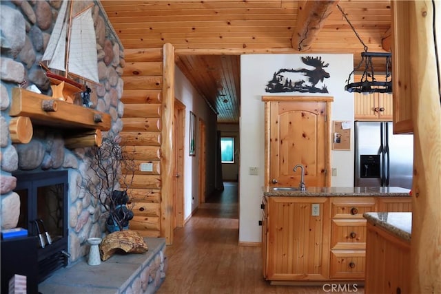 kitchen with a fireplace, a sink, wood finished floors, wooden ceiling, and stainless steel fridge with ice dispenser