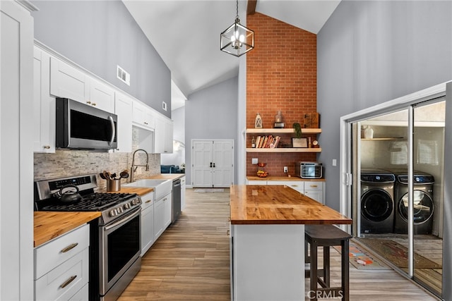 kitchen with wooden counters, backsplash, white cabinetry, and stainless steel appliances