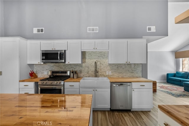 kitchen with decorative backsplash, butcher block countertops, and appliances with stainless steel finishes