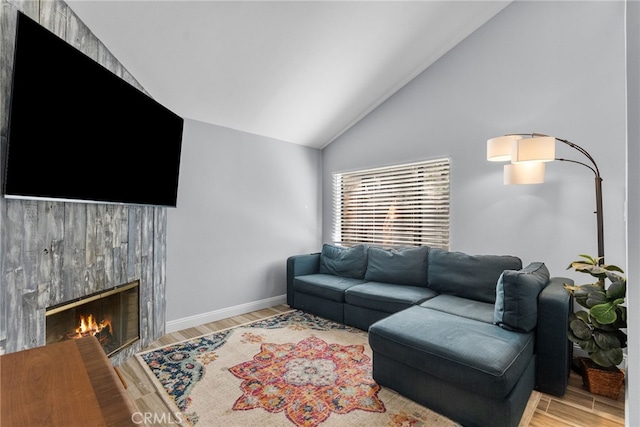 living room with light hardwood / wood-style floors, vaulted ceiling, and a fireplace