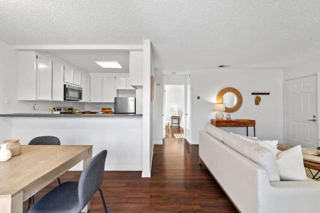 kitchen featuring white cabinets, dark hardwood / wood-style flooring, kitchen peninsula, stainless steel appliances, and a textured ceiling