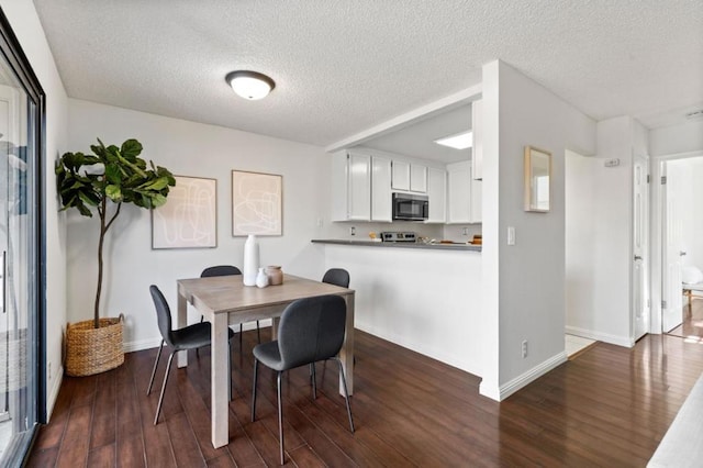 dining room with wood-type flooring and a textured ceiling