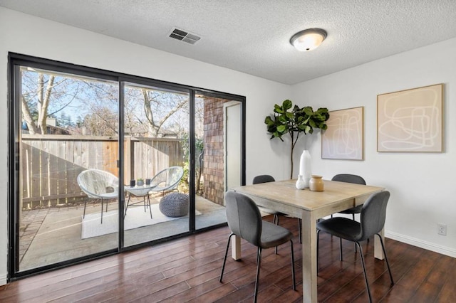 dining space featuring wood-type flooring and a textured ceiling