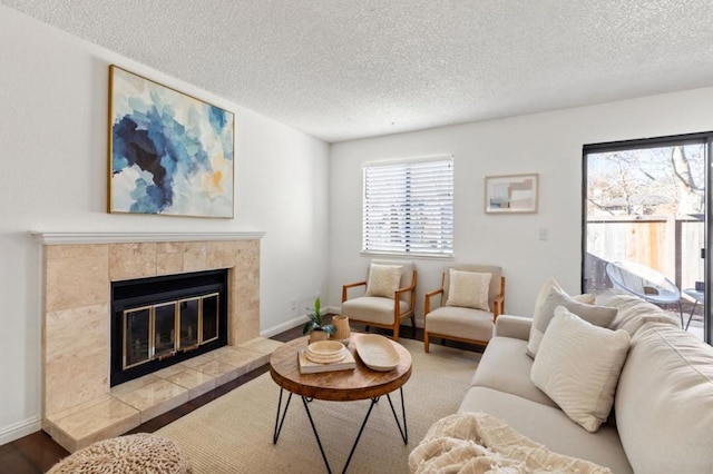 living room featuring hardwood / wood-style flooring, a tile fireplace, and a textured ceiling