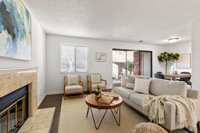 living room with a tile fireplace, a textured ceiling, and light hardwood / wood-style floors