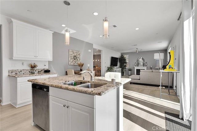 kitchen with sink, white cabinetry, stainless steel dishwasher, and an island with sink