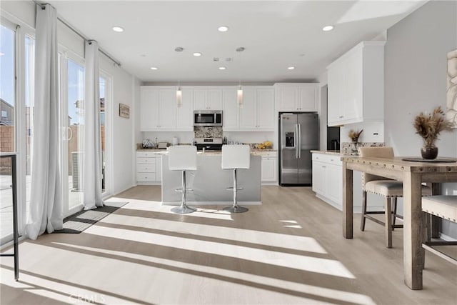 kitchen with a kitchen breakfast bar, pendant lighting, appliances with stainless steel finishes, and a center island