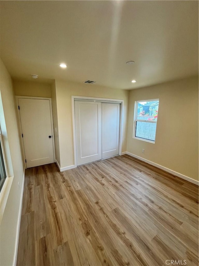 unfurnished bedroom featuring a closet and light wood-type flooring