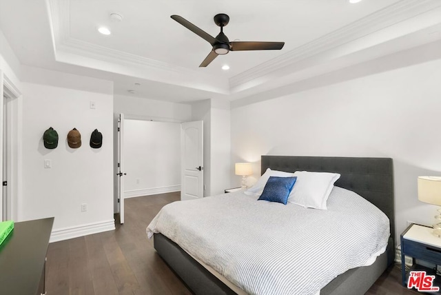 bedroom with ceiling fan, dark wood-type flooring, a tray ceiling, and crown molding