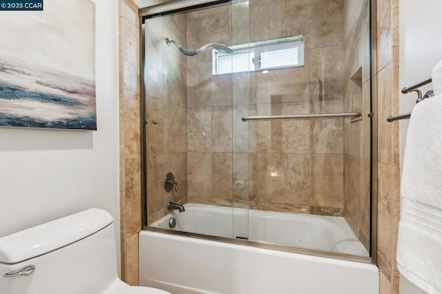 bathroom with toilet and bath / shower combo with glass door