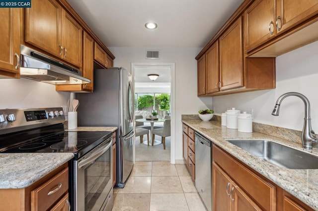 kitchen with sink, stainless steel appliances, light stone counters, and light tile patterned floors