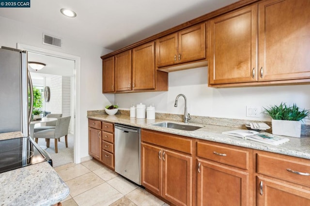 kitchen with sink, light stone counters, light tile patterned flooring, and appliances with stainless steel finishes