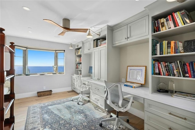 office area with light wood-type flooring, ceiling fan, and built in desk