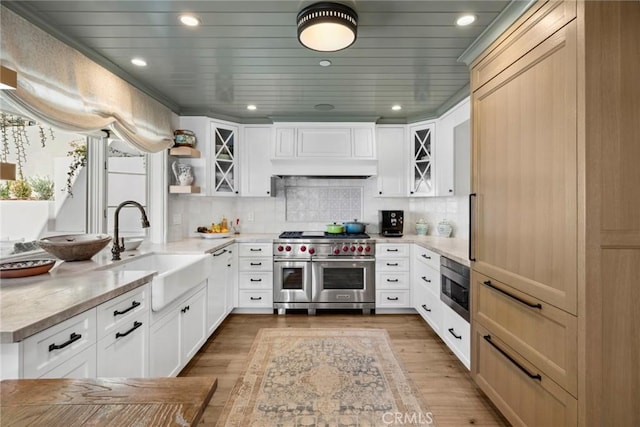 kitchen with light hardwood / wood-style floors, appliances with stainless steel finishes, decorative backsplash, sink, and white cabinets