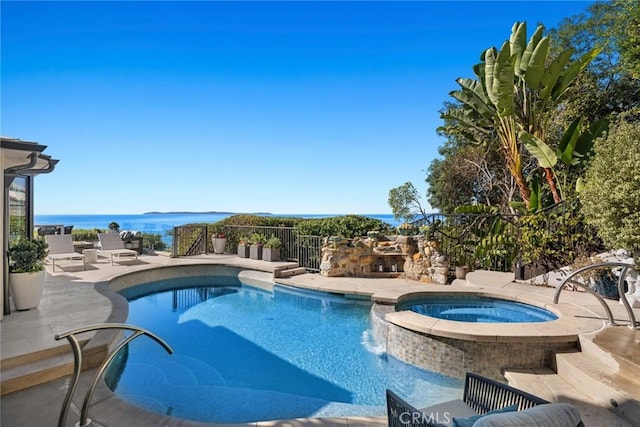 view of pool with an in ground hot tub, a water view, and a patio