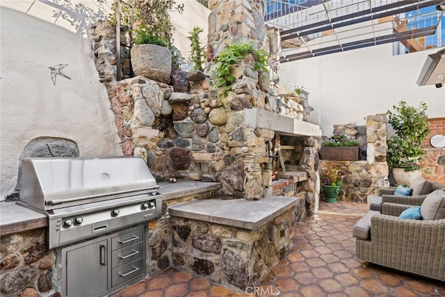 view of patio / terrace with grilling area, an outdoor stone fireplace, and area for grilling