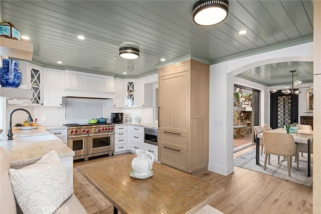 kitchen with sink, double oven range, white cabinets, and tasteful backsplash