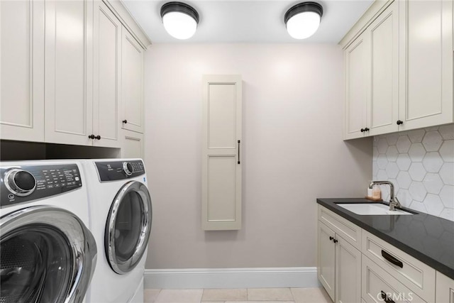 clothes washing area with sink, washing machine and clothes dryer, cabinets, and light tile patterned flooring