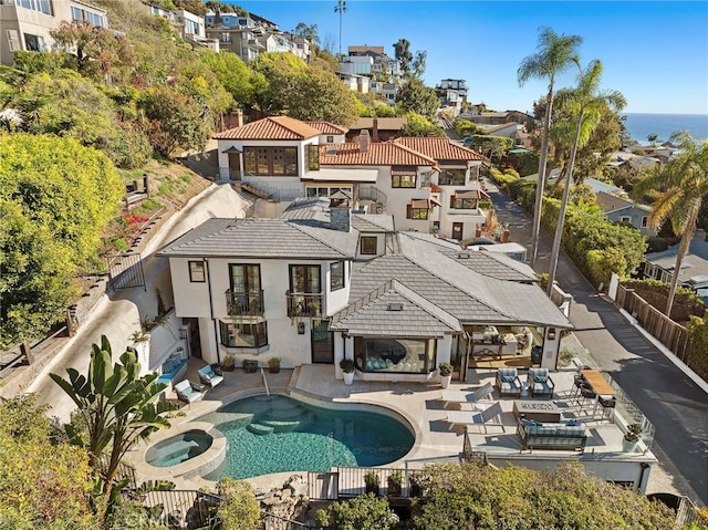 rear view of house with a swimming pool with hot tub and a patio