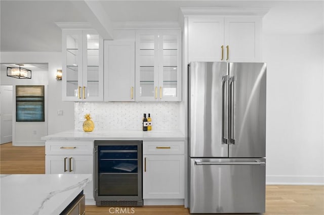 kitchen with light stone countertops, tasteful backsplash, high end fridge, white cabinets, and beverage cooler