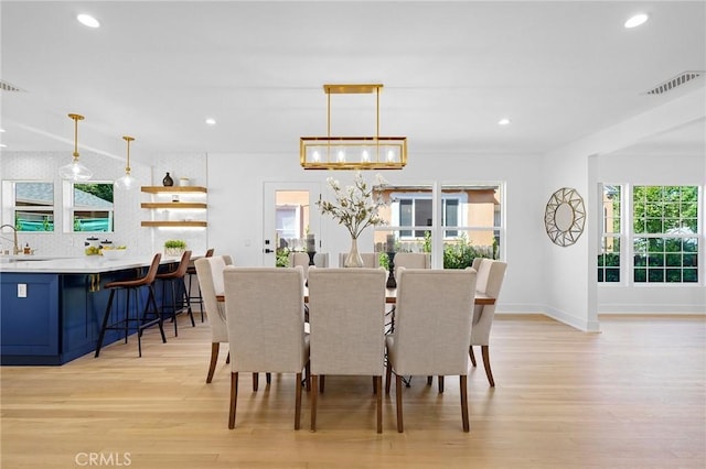 dining room with sink, a notable chandelier, and light wood-type flooring