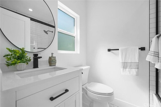 bathroom with a shower with shower door, a wealth of natural light, toilet, and vanity