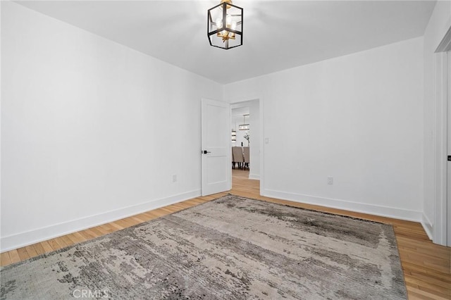 spare room featuring a notable chandelier and wood-type flooring