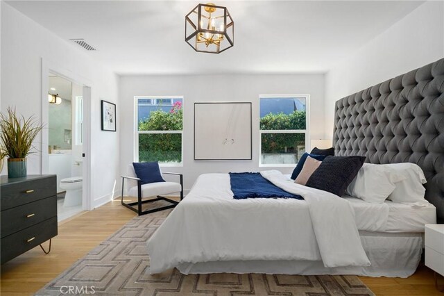 bedroom featuring connected bathroom, an inviting chandelier, light hardwood / wood-style floors, and multiple windows