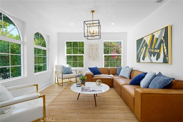 living room with light hardwood / wood-style floors, plenty of natural light, and a chandelier