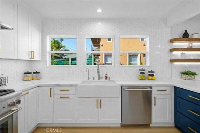 kitchen featuring sink, stainless steel appliances, white cabinets, and light stone countertops