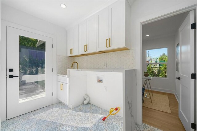 laundry room featuring cabinets, washer hookup, sink, and light wood-type flooring