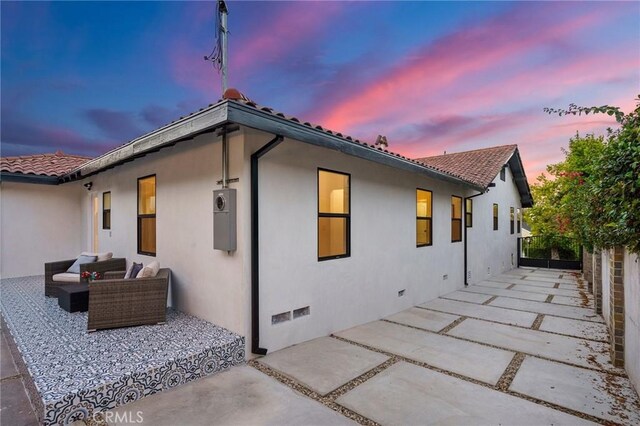 back house at dusk with a patio area and an outdoor hangout area