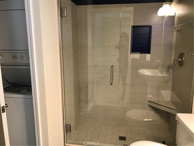 bathroom with an enclosed shower, toilet, and stacked washer and dryer