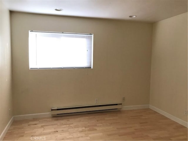 unfurnished room with a baseboard radiator and light hardwood / wood-style floors