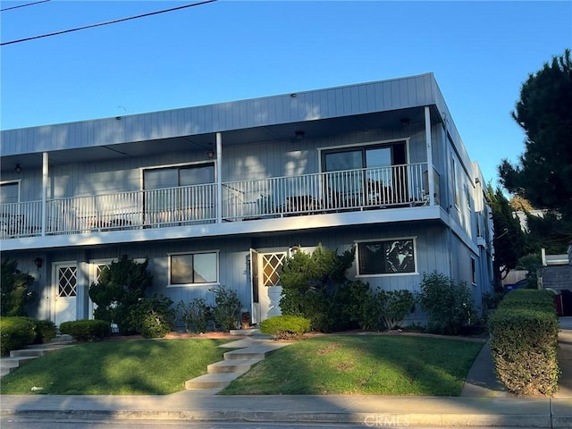 view of front of house with a balcony and a front lawn