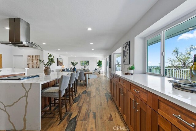 kitchen with a kitchen island, dark wood-type flooring, a breakfast bar area, and island exhaust hood