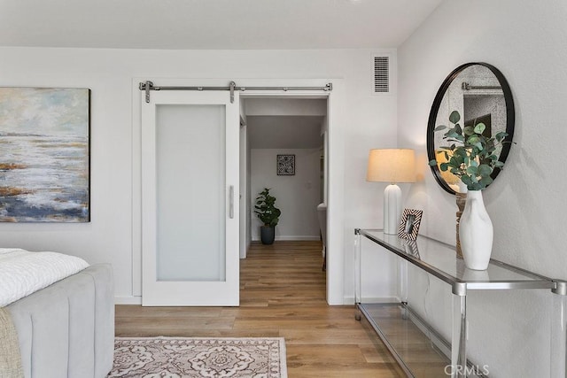 hall with light hardwood / wood-style floors and a barn door