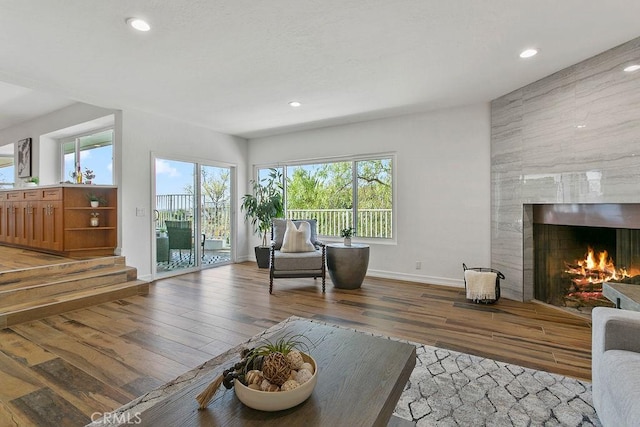 living room featuring plenty of natural light, a tiled fireplace, and light hardwood / wood-style floors