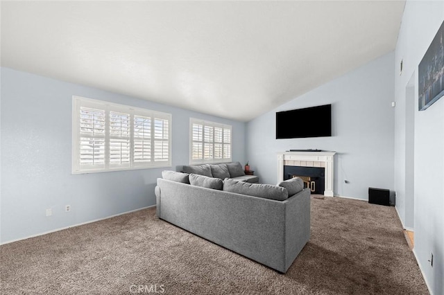 living room with carpet floors, vaulted ceiling, and a tile fireplace