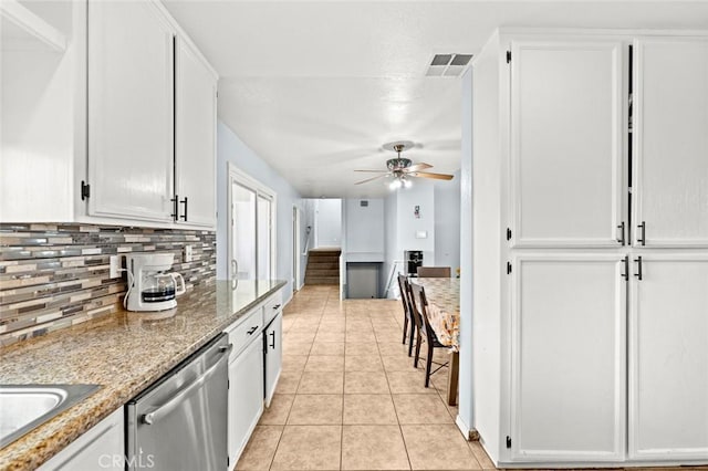 kitchen with white cabinetry, light tile patterned floors, stainless steel dishwasher, and light stone countertops