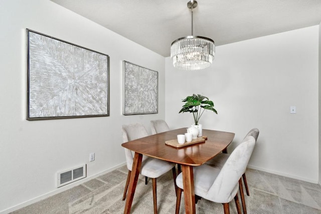 dining room with light colored carpet and a notable chandelier