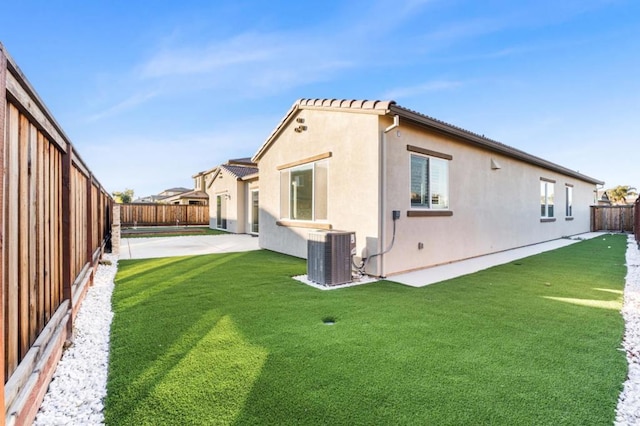 rear view of house featuring a yard, a patio, and central air condition unit