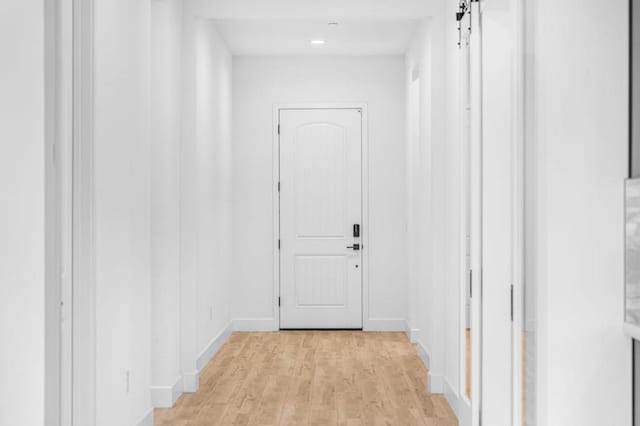 corridor with a barn door and light wood-type flooring